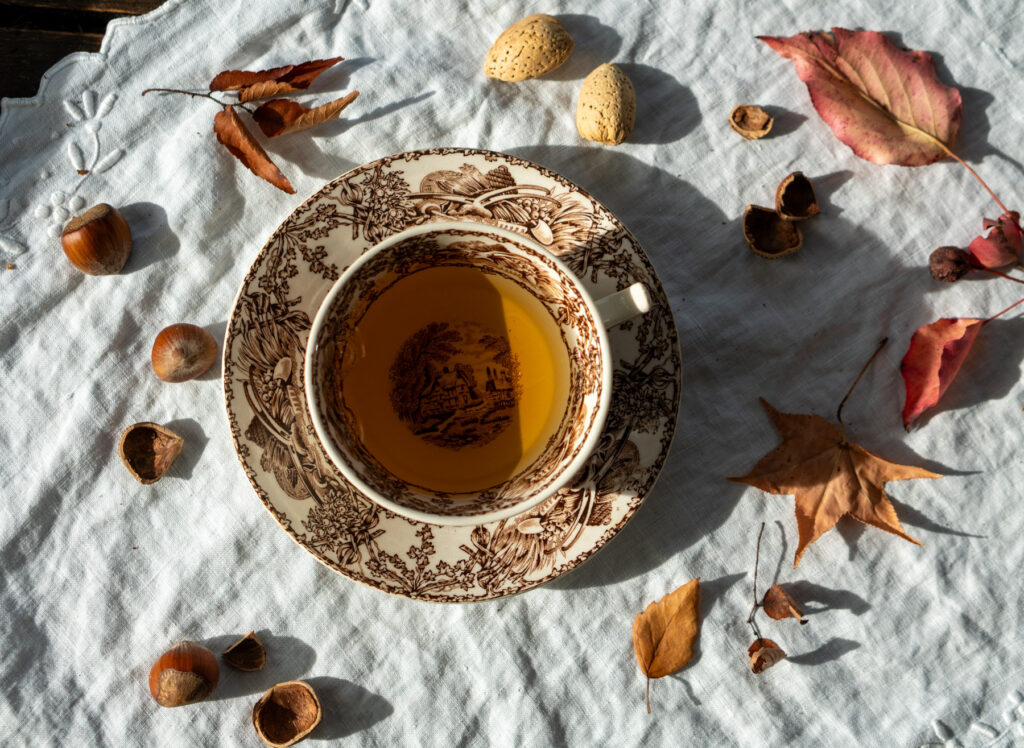 photograph by Jamie Moore of a cup of tea with an assortment of autumn leaves